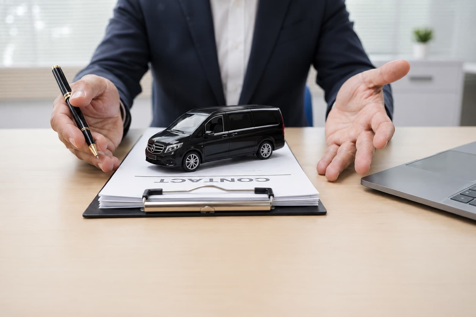 A transfer consultant at a desk ready to help with a booking, a black Mercedes van model in front